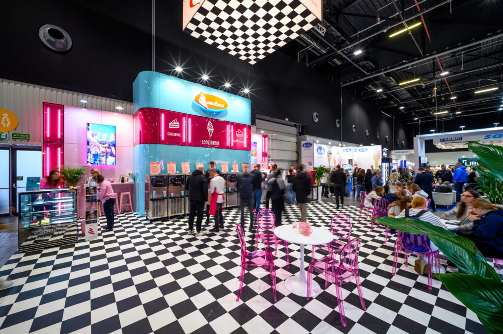 Stoisko na targi w stylu nowoczesnym bazujące na połączeniu różu, błękitów oraz motywu szachownicy - zabudowa marki Drużbice